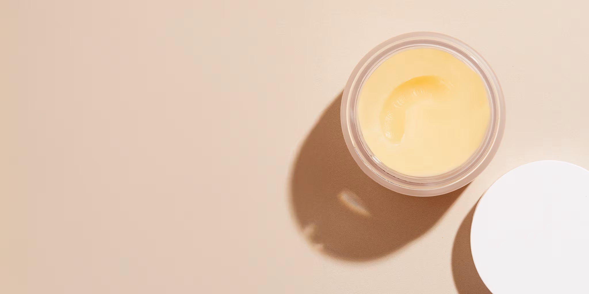 Jar of WONDERBALM open showing the texture on a beige counter.