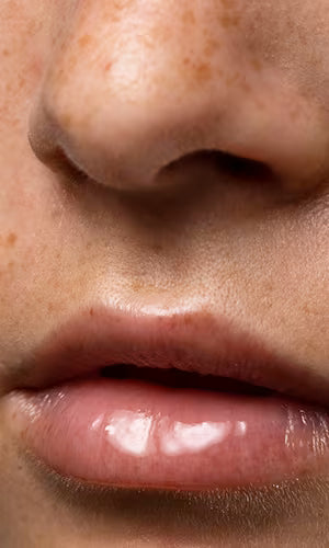 Close-up of a person's nose and lips with a neutral background