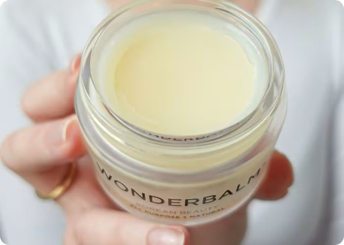 Hand holding a jar of Wonderbalm against a white background