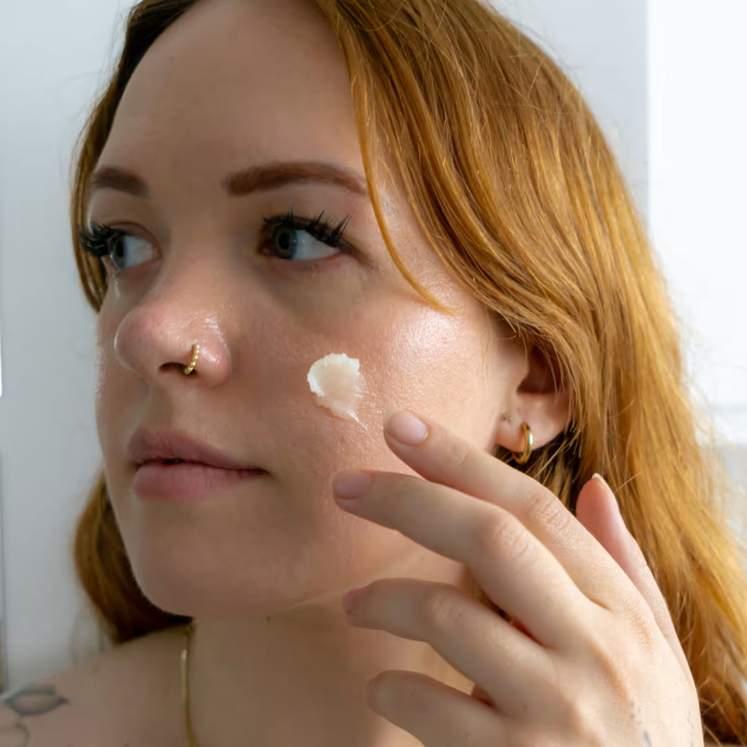 Woman applying WONDERBALM to her face with a neutral background.
